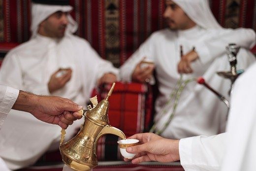 Arab men in a majlis with Arabic coffee served with dates